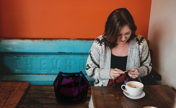 A person knitting out of the Little Swift in a cafe.